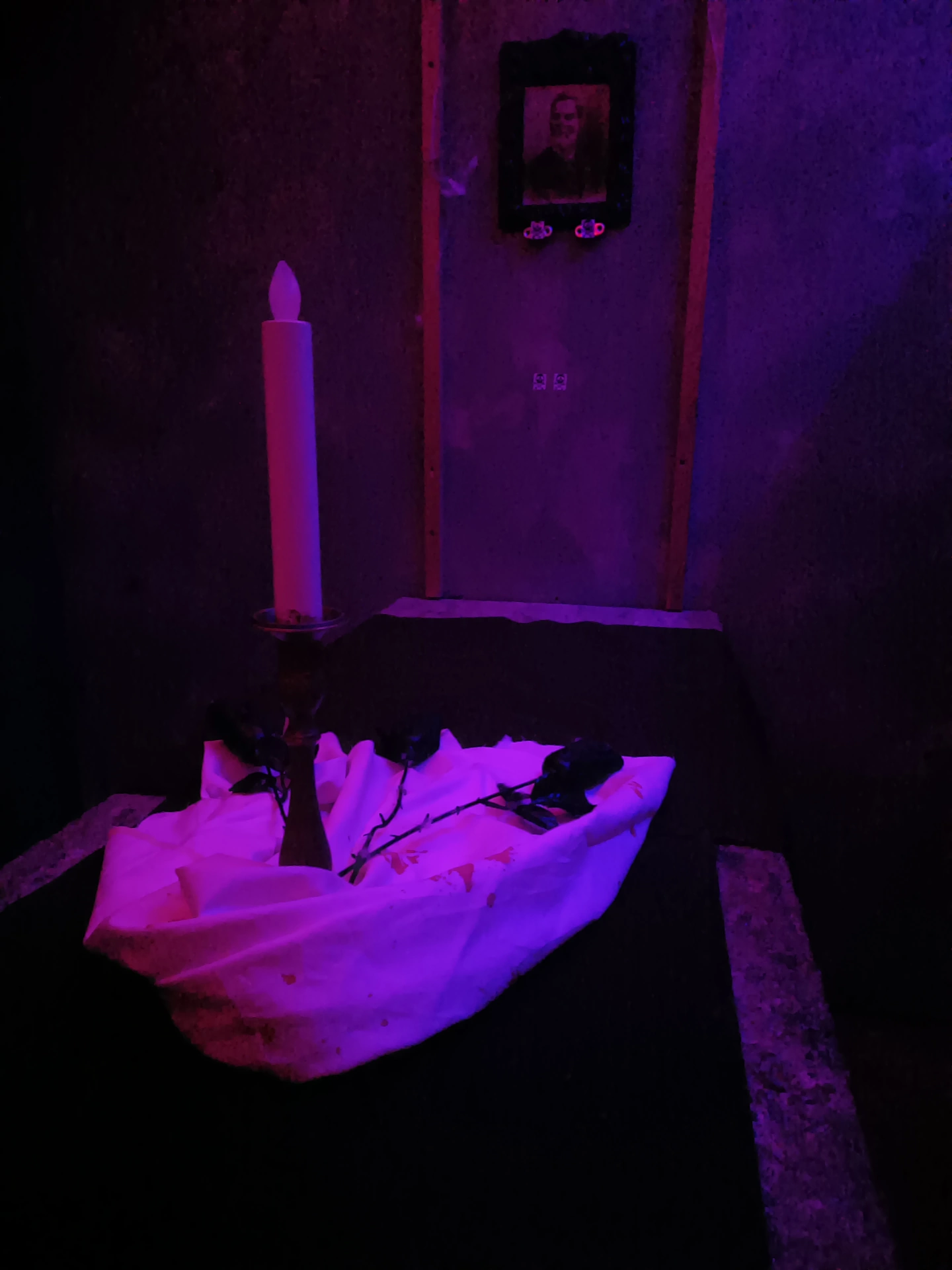 Dettaglio del misterioso tavolo della magia, con candela e ritratto, al centro di un oscuro rituale ne Il Maniero, escape room horror a Milano.
